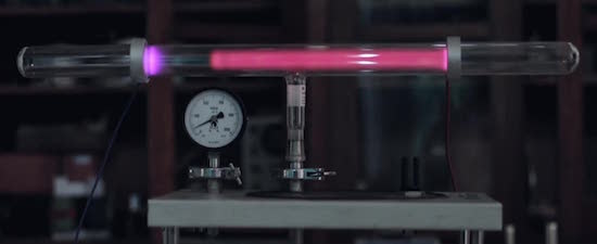 Figure 1: Glow discharge in a low-pressure tube caused by electric current. Like what Faraday saw, the tube shows a dark space between the glows around the cathode (left, negatively charged) and anode (right, positively charged).